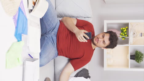 Vertical-video-of-Lazy-man-laughing-at-phone-in-hand-and-not-doing-his-job.